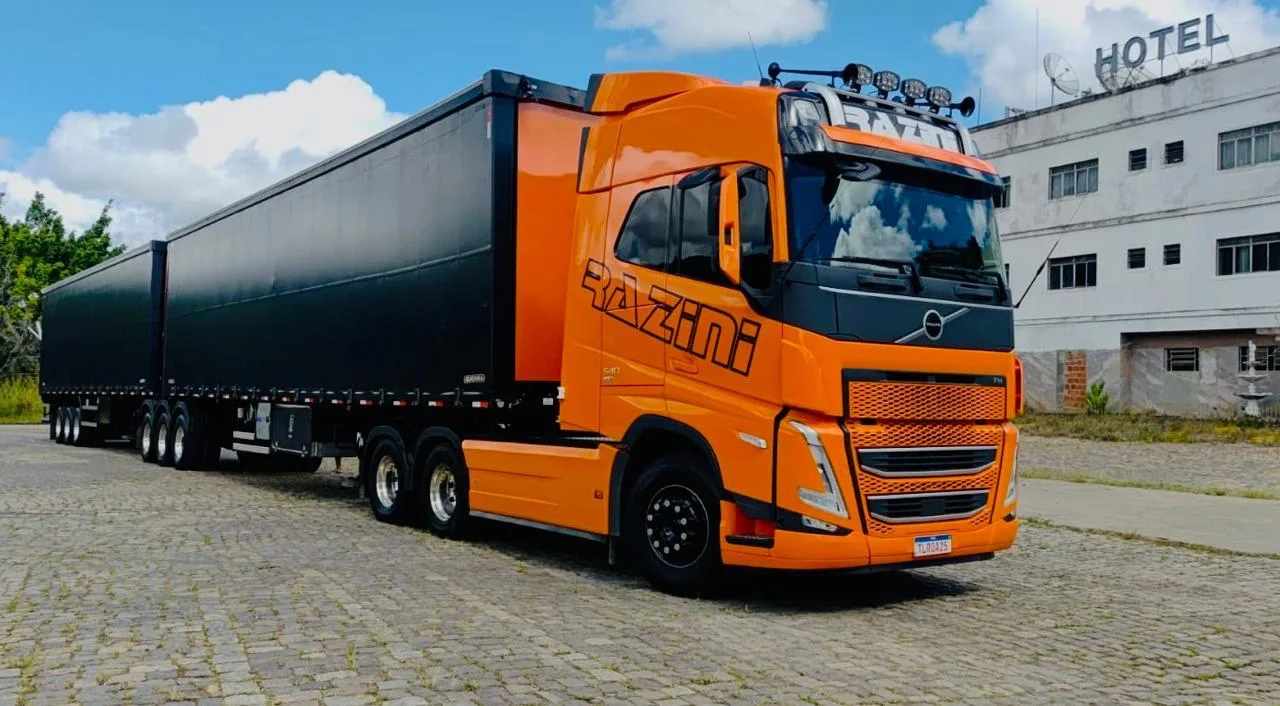 Rodotrem laranja da Razini, Volvo FH 540, com dois semirreboques sob céu azul